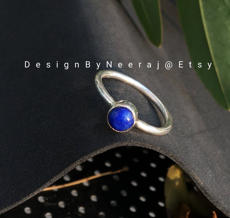 May include: A silver ring with a blue lapis lazuli gemstone. The ring is simple and elegant, perfect for everyday wear.