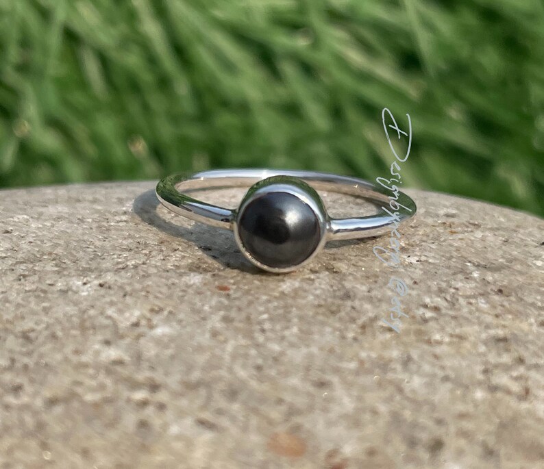 Puede incluir: Un anillo de plata con una piedra preciosa negra. El anillo es simple y elegante.