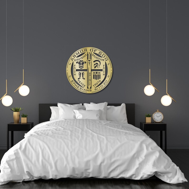 May include: A gold-colored, circular wall hanging with the text "Armor of God" and other religious symbols. The artwork is mounted above a bed with white bedding. The room has dark gray walls and modern lighting fixtures.