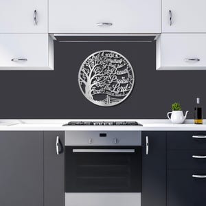 May include: A silver metal wall art piece featuring a tree design within a circular frame. The artwork includes the text "Let everything that has breath praise the Lord" and is mounted on a dark gray wall in a kitchen setting.