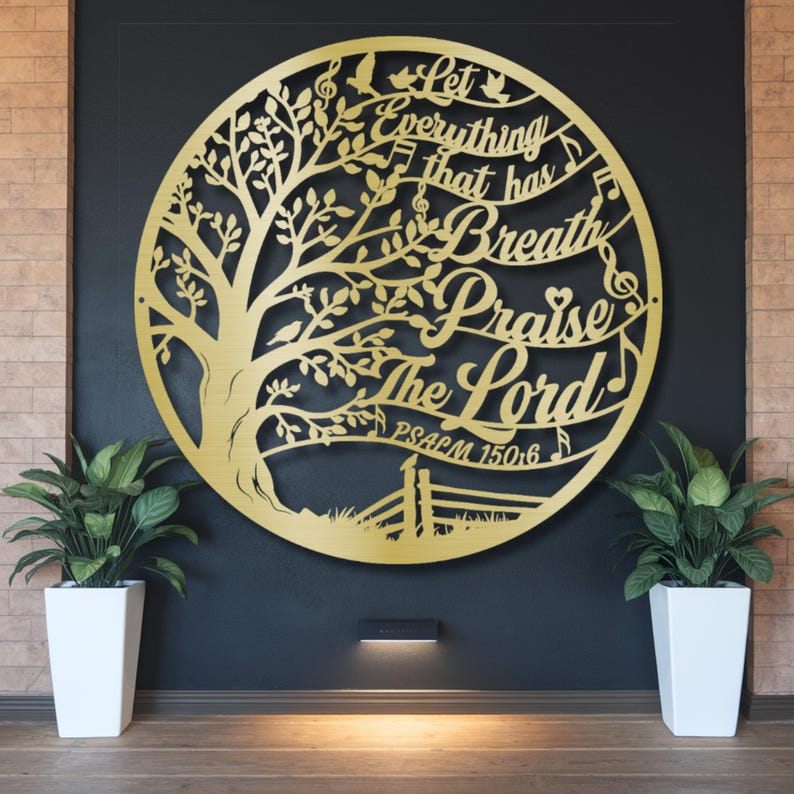 May include: A gold-colored metal wall art piece in a circular design, featuring a tree with musical notes and the words "Let Everything That Has Breath Praise The Lord" and "Psalm 150:6". The art is mounted on a dark wall.