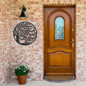 May include: A black metal wall art piece with a tree design and the words "Let everything that has breath praise the Lord" in a circular frame. The art is mounted on a brick wall near a wooden door.