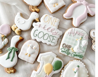 May include: A set of decorated sugar cookies featuring a goose theme. The cookies are decorated with white icing, green and pink accents, and the text "One Silly Goose" and "Alexis is One Silly Goose".