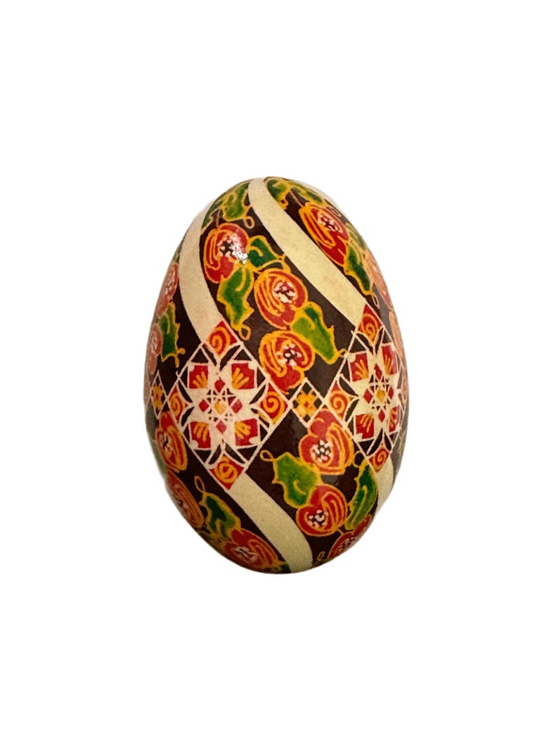 May include: A hand-painted Easter egg with a geometric pattern in shades of brown, white, red, orange, and green.