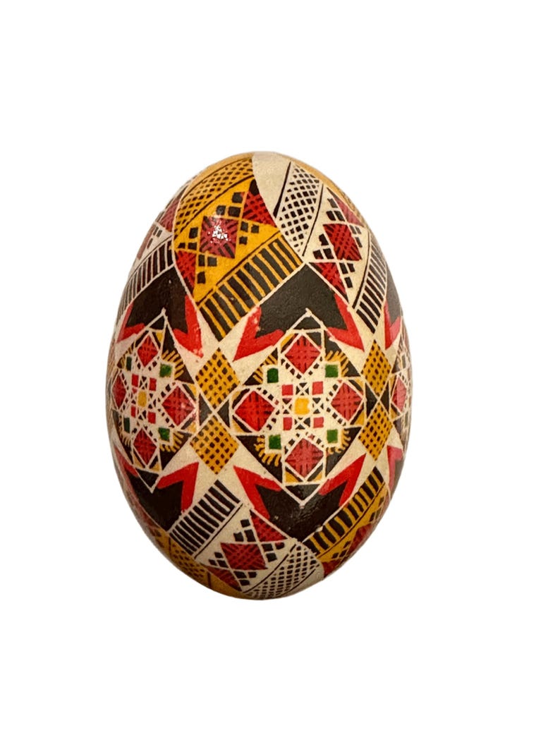 May include: A hand-painted Easter egg with a geometric pattern in red, yellow, black, and green.
