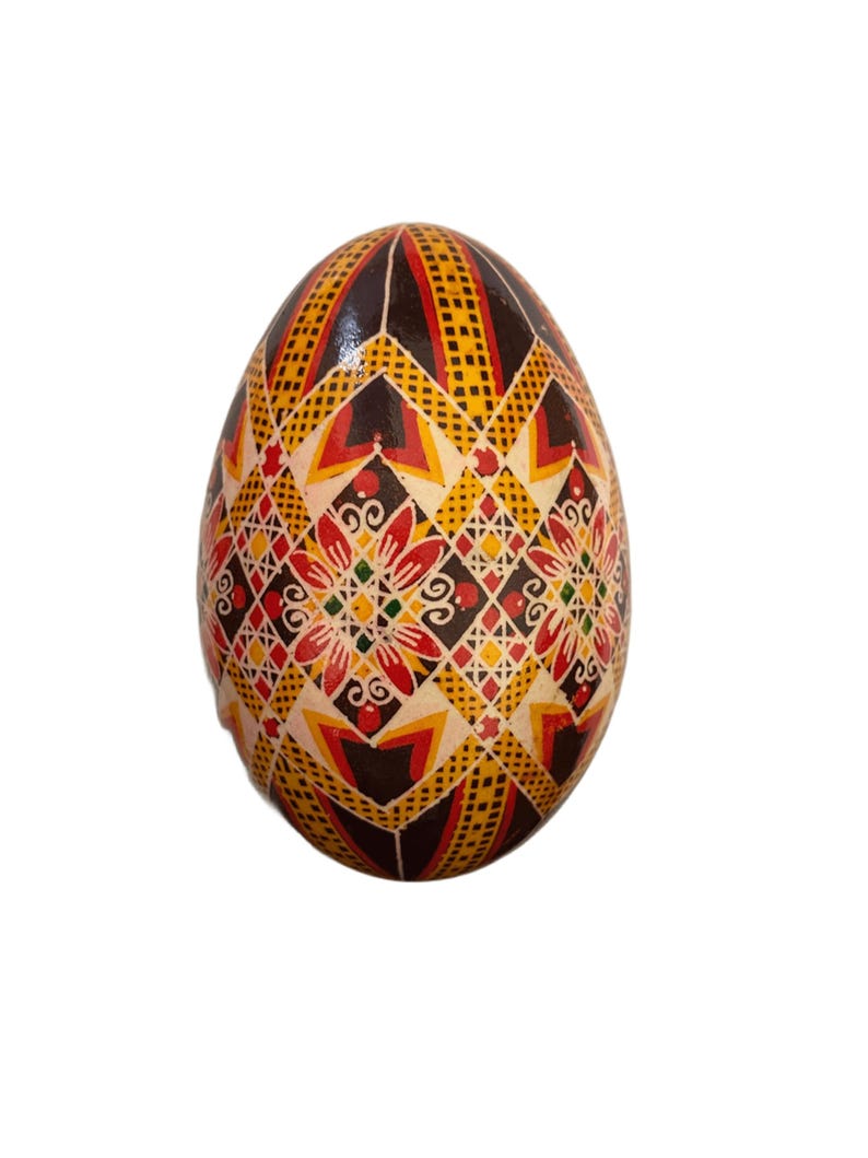 May include: A hand-painted Easter egg with a geometric pattern in shades of red, yellow, black, and white.
