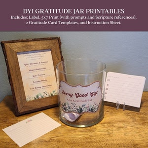Puede incluir: Un juego de tarro de gratitud DIY con un tarro de vidrio transparente, etiqueta, impresión de 5x7, plantillas de tarjetas de gratitud y una hoja de instrucciones. El tarro tiene una etiqueta que dice "Every Good Gift - Our Gratitude Jar". Un marco de madera contiene una impresión con versículos bíblicos.