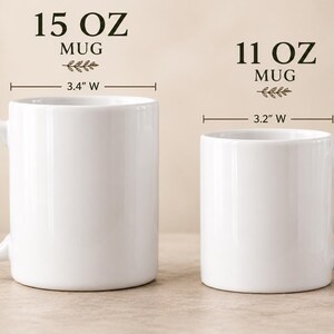 May include: Two white ceramic mugs shown side-by-side. The left mug is labeled 15 OZ MUG, measuring 4.5 inches high and 3.4 inches wide. The right mug is labeled 11 OZ MUG, measuring 3.8 inches high and 3.2 inches wide. Both have handles.