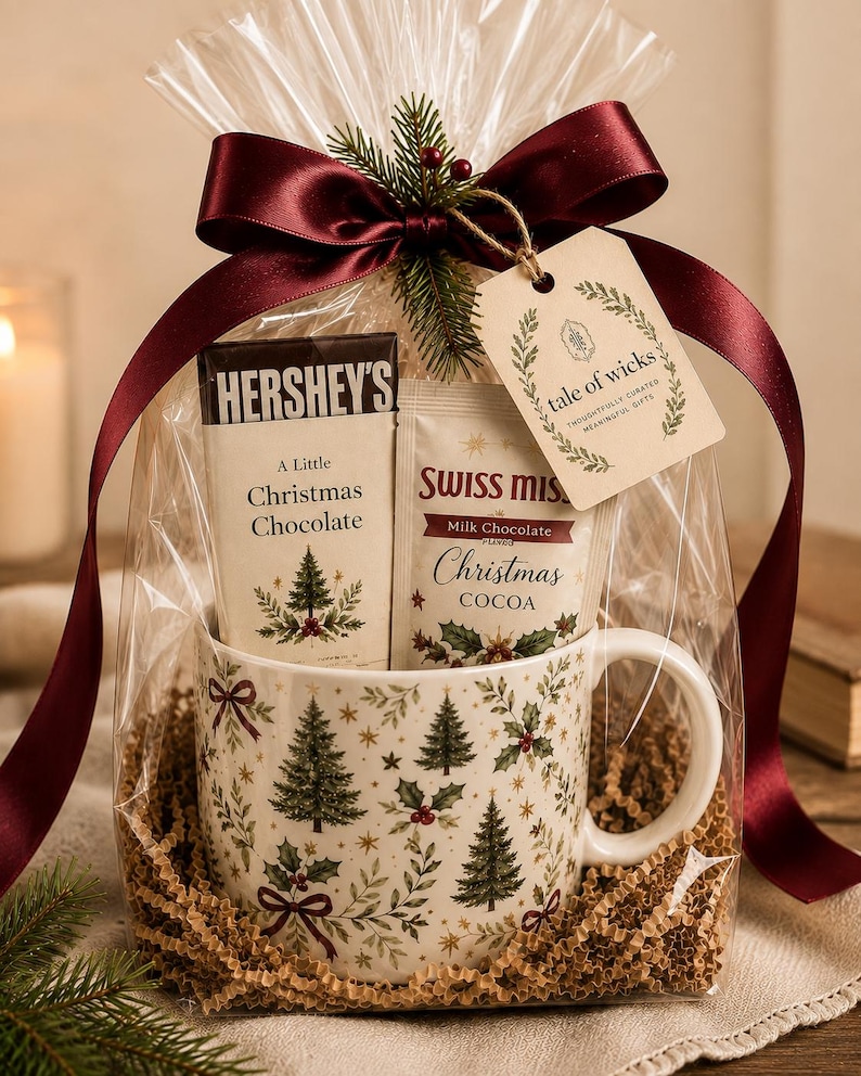May include: A gift set in clear cellophane with a dark red satin ribbon and a tag reading tale of wicks. It contains a white mug with a green Christmas tree and holly pattern, a Hershey's Christmas chocolate bar, and a packet of Swiss Miss cocoa.