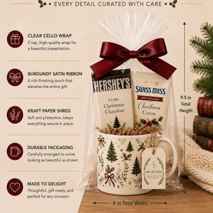 Heritage Christmas mug gift set wrapped in clear cello with burgundy satin ribbon, full-size Hershey’s chocolate and Swiss Miss cocoa, kraft paper shred and Tale of Wicks gift tag, shown ready for Christmas gifting.