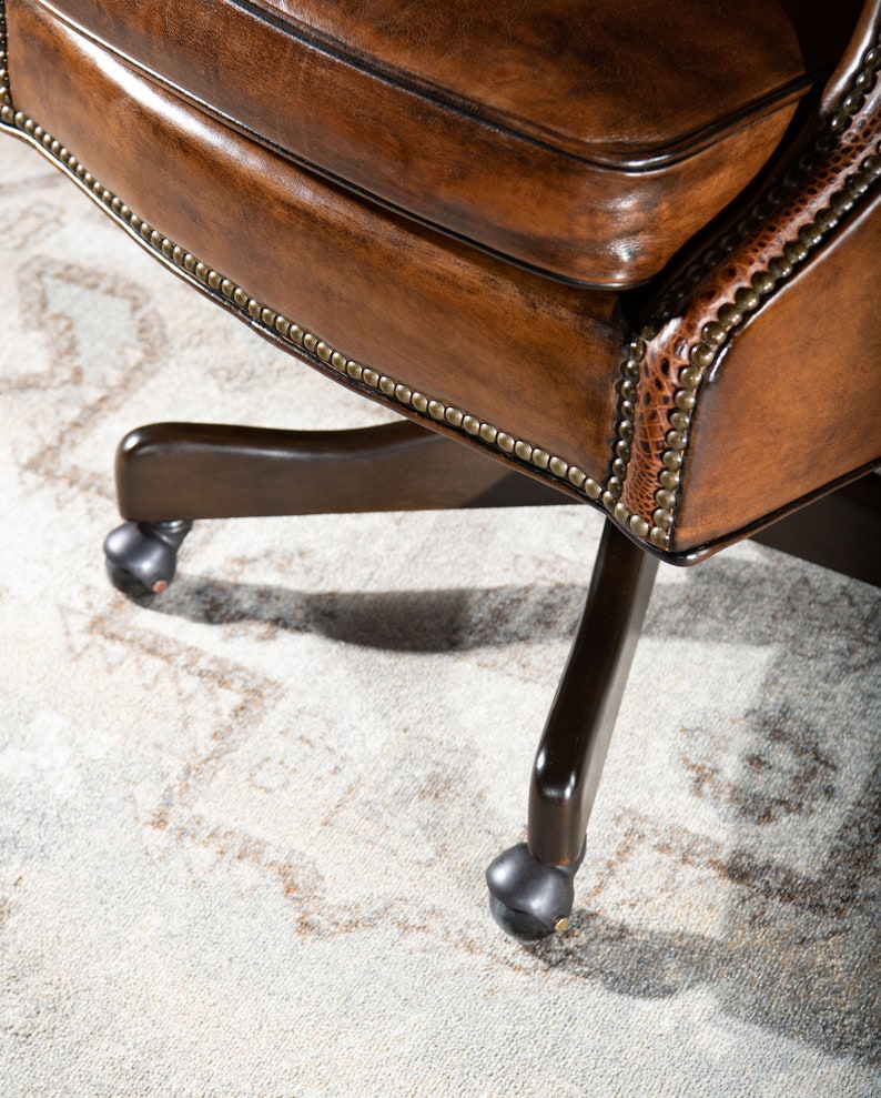 May include: A brown leather office chair with a swivel base and five caster wheels. The chair has a tufted back and a decorative nailhead trim.