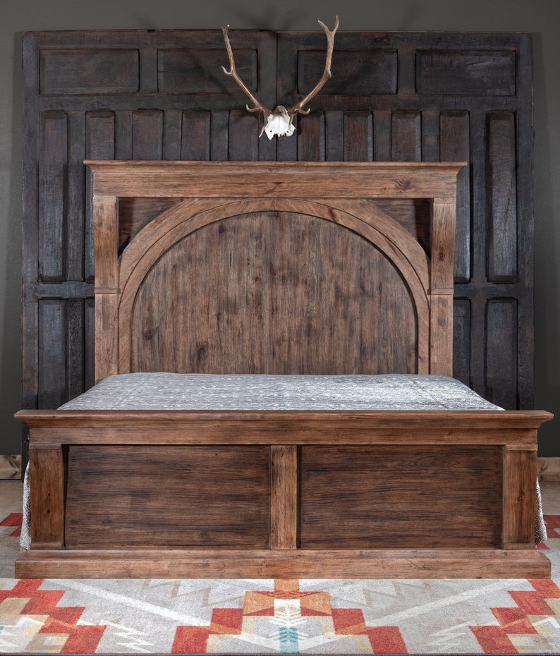 May include: A dark brown wooden bed frame with a headboard featuring an arched design. The bed frame has a simple, rustic style.