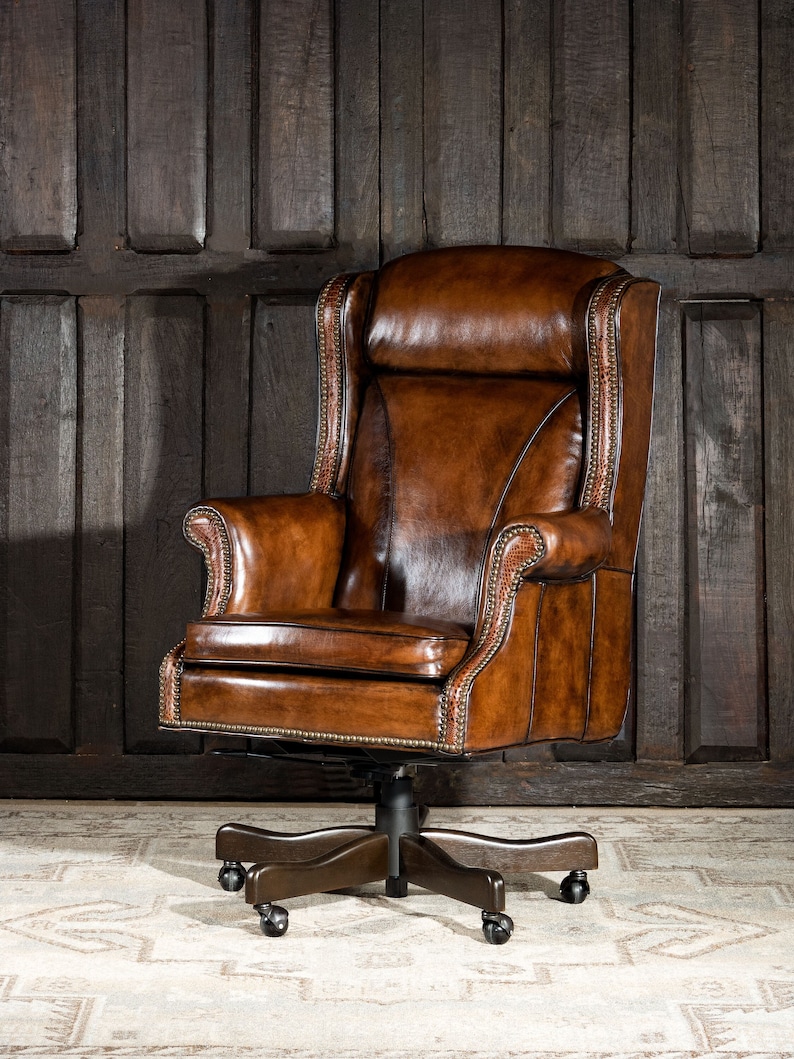May include: A brown leather office chair with a high back and a swivel base. The chair has a tufted design and is on a white rug.