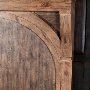 May include: Close-up of a wooden headboard with a rounded top and a dark brown stain. The headboard has a simple, elegant design and would be a great addition to any bedroom.