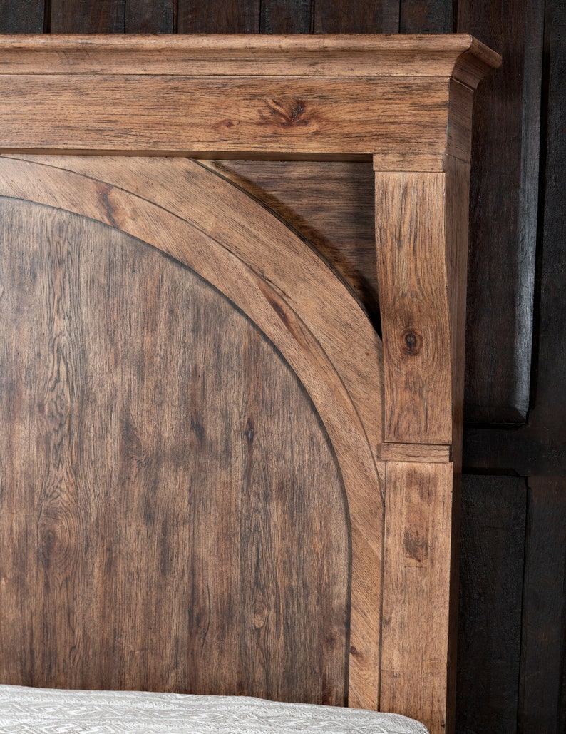 May include: Close-up of a wooden headboard with a rounded top and a dark brown stain. The headboard has a simple, elegant design and would be a great addition to any bedroom.