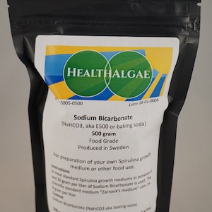 Puede incluir: Una bolsa negra resellable con una etiqueta blanca. La etiqueta tiene el texto "HEALTHALGAE" en un círculo verde. La etiqueta también dice "Bicarbonato de sodio (NaHCO3, también conocido como E500 o bicarbonato de sodio) 500 gramos Grado alimenticio Producido en Suecia" e incluye instrucciones de uso.