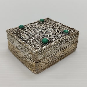 May include: A silver trinket box with an ornate design and turquoise stones on the lid.