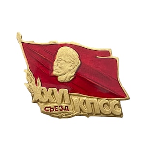 Peut inclure: Une épingle dorée avec un drapeau rouge et un portrait d'un homme. Le drapeau a une étoile dorée et le texte "XVI СЪЕЗД КПСС" en lettres dorées.