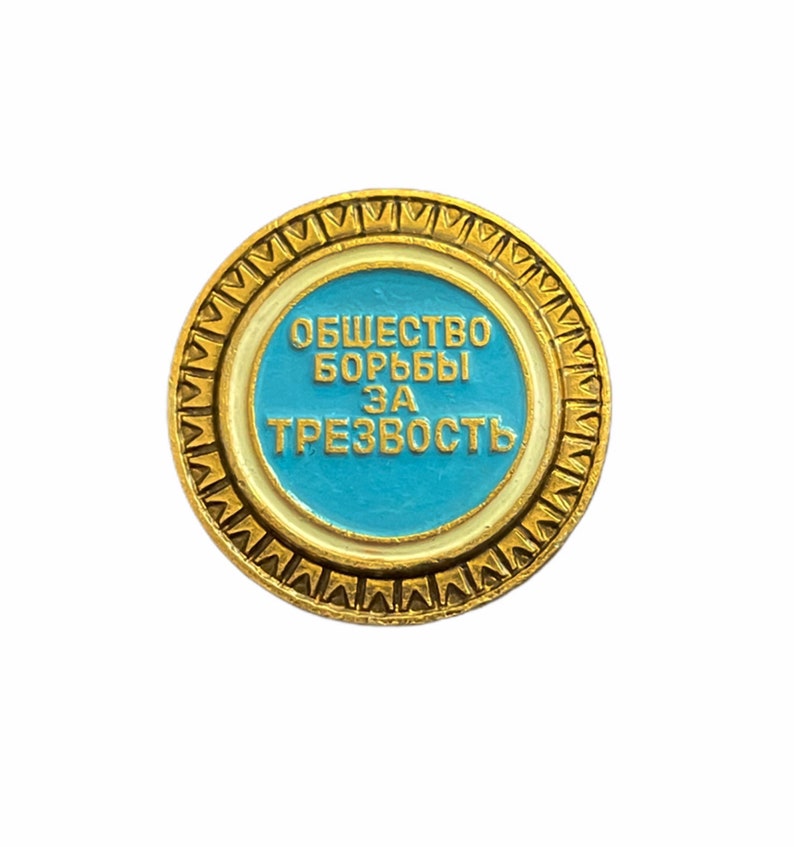 Puede incluir: Un pin de color dorado con un centro azul y un borde blanco. El texto en el pin dice "Общество борьбы за трезвость".