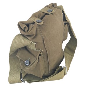 Pu&ograve; includere: Una borsa di tela marrone con una lunga tracolla e una chiusura a lembo. La borsa ha una piccola tasca sul davanti e due bottoni sul lembo.