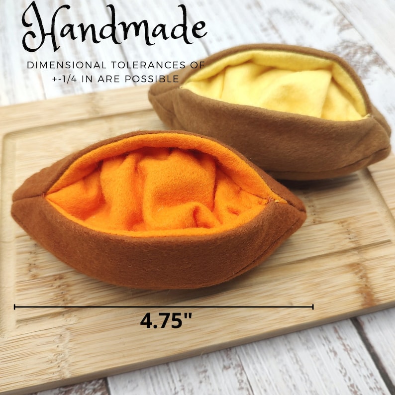 Puede incluir: Dos bolsas de tela marr&oacute;n hechas a mano con forro de tela naranja y amarillo. Las bolsas miden 4,75 pulgadas de largo. El texto "Handmade" y "Dimensional Tolerances of +1/4 in are possible" est&aacute; impreso en la superficie de madera.