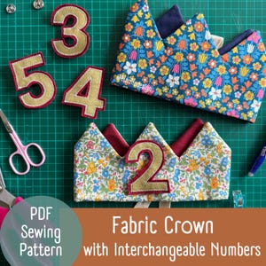 Może przedstawiać: Korony z tkaniny z wymiennymi numerami, z kwiatowym wzorem i złotymi numerami. Obraz zawiera numery 2, 3, 4 i 5, a także parę różowych nożyczek. Tekst brzmi "PDF Sewing Pattern" i "Fabric Crown with Interchangeable Numbers."