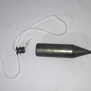 May include: A silver plumb bob with a pointed tip and a threaded top. A white string is attached to the top.