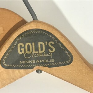 May include: Two wooden hangers with a black label that reads "GOLD'S Clothing MINNEAPOLIS".
