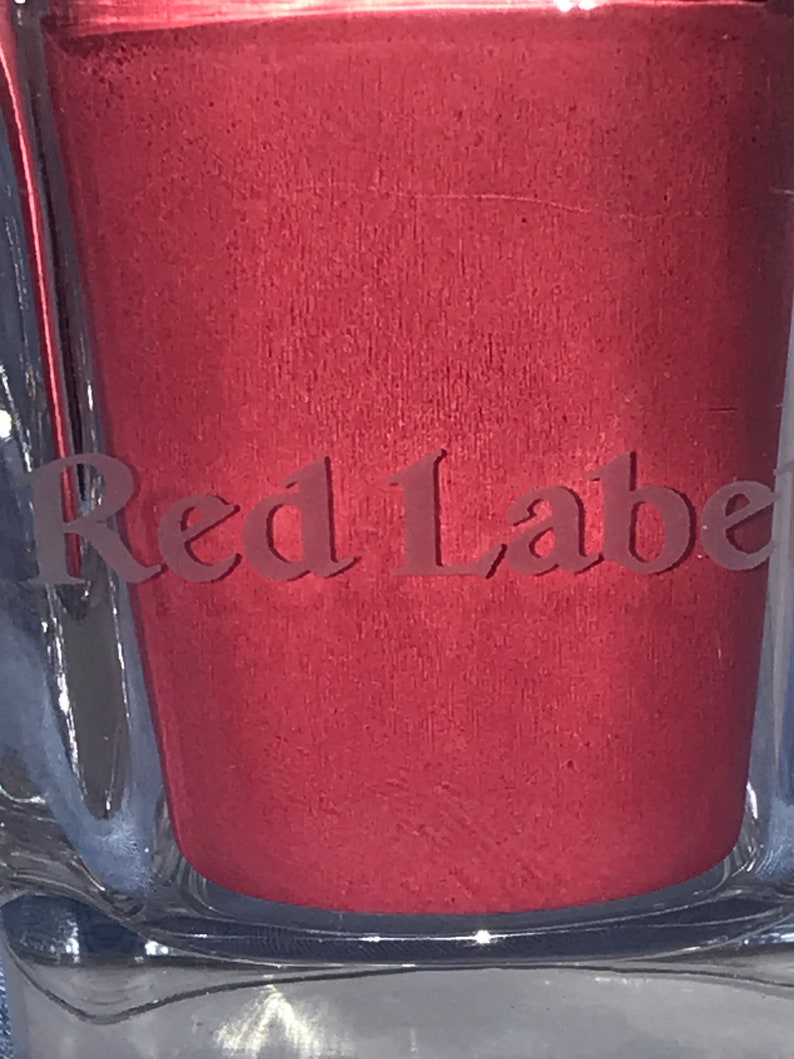 May include: Close-up of a red glass bottle with the words "Red Label" embossed on the front.