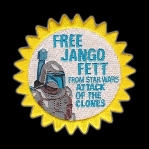 May include: A white and yellow embroidered patch featuring a cartoon image of Jango Fett from Star Wars: Attack of the Clones. The text "Free Jango Fett from Star Wars Attack of the Clones" is embroidered in blue and white.