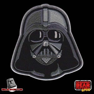 May include: A black and grey embroidered patch of Darth Vader's face from Star Wars. The patch is a detailed depiction of the iconic villain's helmet and features a black background with grey embroidery.
