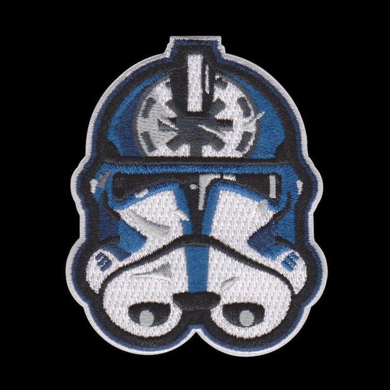 Puede incluir: Parche bordado con un dise&ntilde;o de casco azul y blanco. El parche tiene un borde negro y representa un casco estilizado con detalles intrincados. El dise&ntilde;o incluye un emblema circular y rasgos faciales sim&eacute;tricos, sobre un fondo negro.