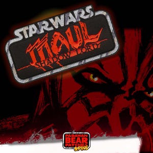 May include: A rectangular patch with the text "STAR WARS MAUL SHADOW LORD" in red and white lettering. The patch is black with a silver border. The background features a red illustration of a character's face. The bottom right corner has a logo that says "PADAWAN BEAR PATCHES & PINS."