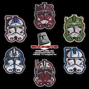 May include: Embroidered patches featuring various designs of Republic Commanders and ARC Troopers helmets. The patches are in red, green, blue, and white, with detailed stitching and a black background. The word "BUCKETS" is also visible.