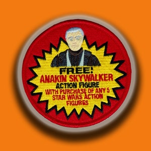 May include: A red, yellow and black embroidered patch with a starburst design. The patch features a cartoon image of Anakin Skywalker and the text "FREE! ANAKIN SKYWALKER ACTION FIGURE WITH PURCHASE OF ANY 5 STAR WARS ACTION FIGURES".