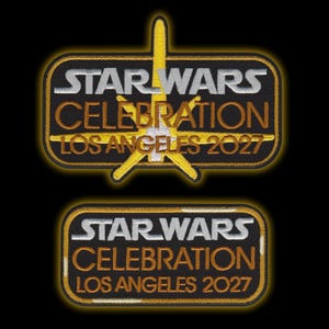 Puede incluir: Dos parches rectangulares bordados con el texto STAR WARS CELEBRATION LOS ANGELES 2027. El parche superior incluye un gran emblema en forma de estrella amarilla y blanca detrás del texto. Ambos parches tienen fondos negros con bordes dorados.
