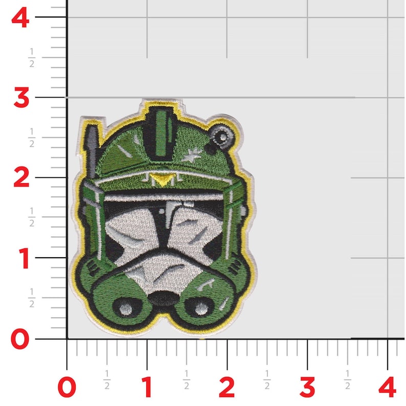 Puede incluir: Parche bordado con un dise&ntilde;o de casco verde y blanco. El parche tiene un borde amarillo y costuras detalladas. El dise&ntilde;o del casco recuerda a un casco de soldado clon. El parche mide aproximadamente 7.6 cm de altura.