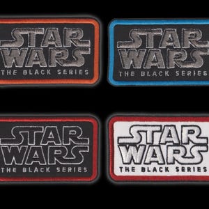 May include: Four rectangular embroidered patches featuring the Star Wars The Black Series logo. Each patch has a black centre with silver text and a distinct border colour: orange, blue, red, and a white patch with a red border and black text.