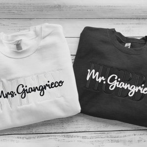 May include: Two white and black sweatshirts with the text "Mrs. Giagrieco" and "Mr. Giagrieco" embroidered on them.