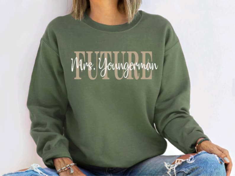 May include: A green sweatshirt with the text "FUTURE Mrs. Youngerman" in brown and white lettering.