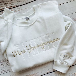 May include: White sweatshirt with gold embroidery that says "Mrs. Youngerman" and "10.18.24" on the sleeve.