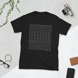Könnte beinhalten: Schwarzes T-Shirt mit einem weißen Grafikdesign aus einem sich wiederholenden Muster aus Wellen und Quadraten. Der Text "Kinfolk Store" ist unten im Design in Weiß gedruckt.
