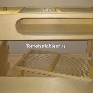 May include: A wooden tortoise table with a mesh top and a pull-out drawer. The table has a built-in hideaway for the tortoise. The text "Tortoisetablesrus" is printed on the side of the table.