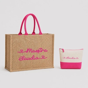 Può includere: Una borsa tote in iuta con manici rosa e testo ricamato "Maestra Claudia". È presente anche un piccolo beauty case abbinato con base rosa e il nome "Claudia".