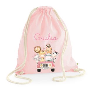 Pode incluir: Mochila rosa de cordão com o nome "Giulia" estampado na frente. A mochila apresenta uma imagem de desenho animado de um jipe rosa com animais no topo, incluindo um leão, uma girafa, um macaco, um elefante e uma zebra. O jipe tem a palavra "Safari" impressa na placa.