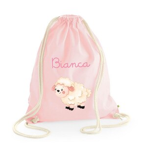 Pode incluir: Saco de cordão rosa com uma ilustração de ovelha branca e o nome "Bianca" impresso na frente.