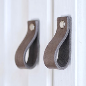 May include: Two gray leather cabinet pulls with silver metal hardware.