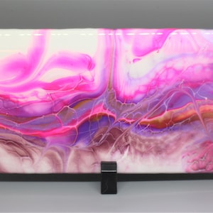 May include: Abstract painting on a white canvas with pink, purple, and gold swirls and lines.
