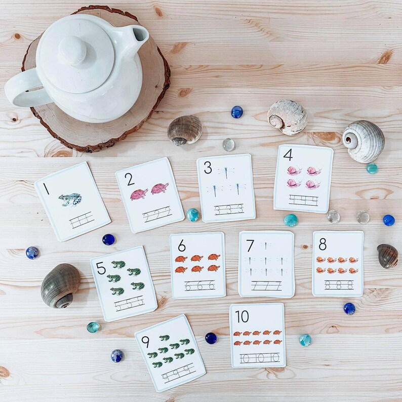 May include: A set of ten colorful flashcards with numbers 1 through 10. Each card features a different number of animals, including frogs, turtles, and snails. The cards are designed for learning to count and number recognition.