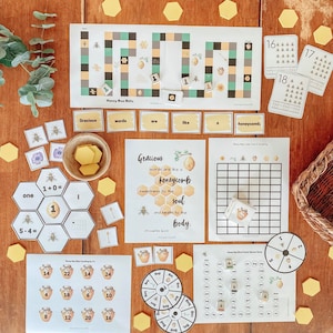 Puede incluir: Materiales educativos con temática de abejas, que incluyen un juego de mesa, tarjetas de palabras y rompecabezas de números. El conjunto presenta un diseño de panal, con el texto "Honey Bee Bitz" y "Gracious words are like a honeycomb".